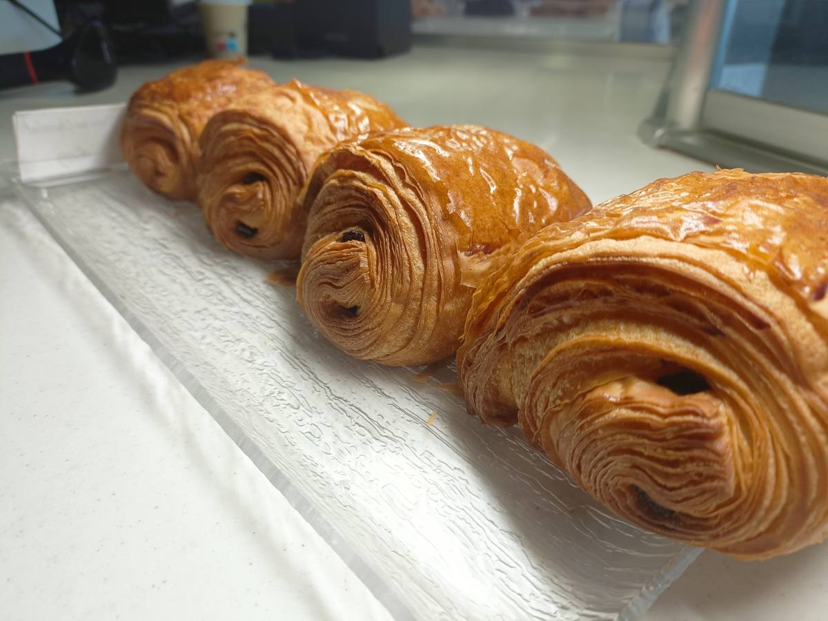 La boulangerie Cornu, située à La Farlède dans le Var, figure parmi les établissements sélectionnés pour participer à la 11e saison de l'émission "La meilleure boulangerie de France" sur M6. Cette année, le jury, composé du boulanger Bruno Cormerais, de la chef pâtissière Noëmie Honiat et du chef étoilé Michel Sarran, aura la lourde tâche de juger les candidats. Avant d'atteindre la finale nationale, la boulangerie Cornu devra se distinguer lors des duels régionaux à Nice, où elle représentera fièrement le Var aux côtés de deux autres boulangeries locales. Une Affaire Familiale de Passion et de Tradition Fondée par Christophe et Nadia Cornu, la boulangerie est désormais rejointe par leurs enfants, Alexis et Cécilia, perpétuant ainsi une tradition familiale. La sélection de la boulangerie pour l'émission a été motivée par des recommandations de clients satisfaits, une preuve de l'excellence de leur artisanat. Un Engagement pour le Fait-Maison L'équipe Cornu met un point d'honneur à préparer tous ses produits de A à Z, garantissant l'authenticité et la qualité de sa boulangerie, viennoiserie, pâtisserie, chocolaterie, glacerie et macarons. Le tournage de l'émission s'est déroulé dans leur établissement de 350m2, un moment décrit par Alexis comme une expérience enrichissante. Des Produits Uniques et Locaux Durant l'émission, les chefs ont eu l'occasion de déguster des produits aléatoires, ainsi qu'une recette spéciale mettant en avant un produit local, concoctée en seulement deux heures. Ces créations uniques seront disponibles en boutique dès 2024, bien que les détails de leur identité et recette restent confidentiels pour l'instant. Une Équipe de Passionnés La boulangerie Cornu ne se repose pas uniquement sur ses fondateurs. L'établissement compte 42 employés, dont un chef boulanger, Moustapha, qui fait partie de l'équipe depuis 18 ans, ainsi qu'un chef tourier, un chef pâtissier et un chef cuisinier. Leur savoir-faire a déjà été reconnu localement avec une troisième place au concours de la meilleure viennoiserie du Var pour leur pain au chocolat. Innovation et Accessibilité En plus de son savoir-faire artisanal, la boulangerie farlédoise a lancé une application pour offrir un service de livraison à domicile dans un rayon de 12 km, disponible 7 jours sur 7, en 30 minutes, aux mêmes prix qu'en boutique, témoignant de leur volonté d'innovation et d'accessibilité. pains au chocolat ou croissant